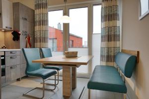 cocina con mesa de madera y sillas azules en Helios, en Büsum