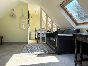 a living room with a black couch and a staircase at Forest Studio Apartment gated Parking on 2 acres Garden in Chislehurst