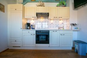 a kitchen with white cabinets and a black appliance at Klaar Kimming Haus Wattwurm in Büsum +6 photos