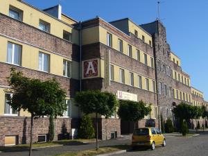 a yellow car parked in front of a brick building at Hotel Arkadia in Legnica