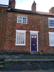 a brick house with a purple door and white windows at The Little House Louth in Louth