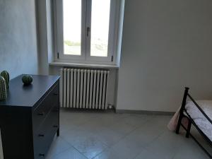 Zimmer mit einem Fenster, einer Kommode und einem Schreibtisch in der Unterkunft CASA FRIDA in Canelli