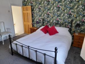 a bedroom with a large bed with red pillows at The Little House Louth in Louth