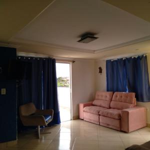 sala de estar con sofá rosa y cortinas azules en Alta baixa temporada, en Cabo Frío