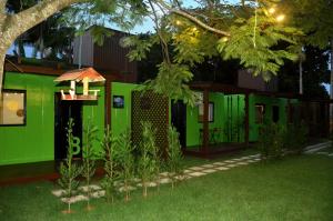 a green house with a tree in the yard at Innbox - Porto Belo in Porto Belo