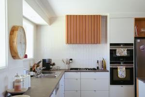 una cocina con armarios blancos y un reloj en la pared en Miravino – breathtaking vineyard views en McLaren Vale