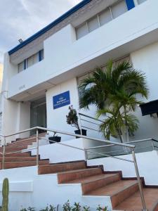 a building with stairs and a palm tree in front of it at Hotel Estefanía Princess 84 in Barranquilla