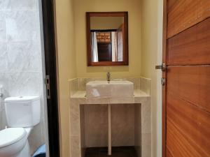 y baño con lavabo, aseo y espejo. en Sienna Resort, en Maratua Atoll
