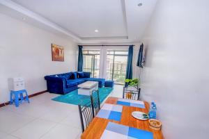 een woonkamer met een blauwe bank en een tafel bij Lathembo Serviced Apartments in Nairobi