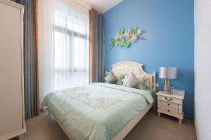a blue bedroom with a bed and a window at WESU Weisu Executive Apartment Shenzhen Shenda Metro Store in Shenzhen