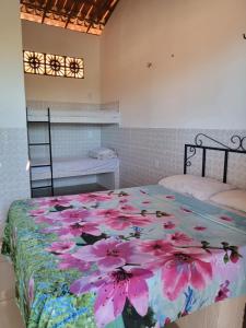 a bedroom with a bed with pink flowers on it at Pousada Paradise in Canoa Quebrada