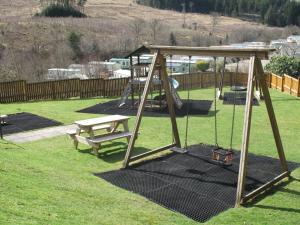 a swing set and a bench in a yard at Corriefodly Holiday Park in Blairgowrie