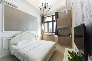 een slaapkamer met een groot wit bed en een televisie bij WESU Weisu Executive Apartment Shenzhen Shenda Metro Store in Shenzhen