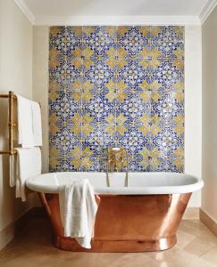 a bath tub in a bathroom with a blue and yellow wallpaper at Villa Sant'Andrea, A Belmond Hotel, Taormina Mare in Taormina +76 photos