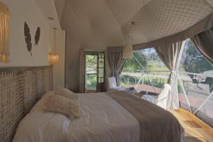 a bedroom with a large bed and a large window at Glamping Tafí del valle in Tafí del Valle