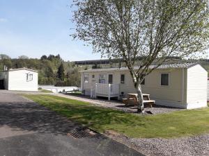 un camping con una mesa de picnic y un árbol en Corriefodly Holiday Park, en Blairgowrie