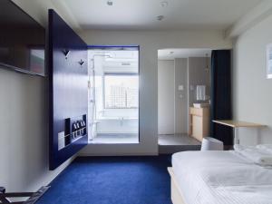 a bedroom with a bed and a bathroom with a tub at The Share Hotels Lyuro Tokyo Kiyosumi in Tokyo