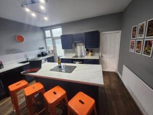 uma cozinha com um balcão e alguns bancos cor-de-laranja em House near restaurants, park and pubs, perfect for pets! em Bristol