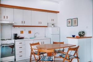 a kitchen with white cabinets and a table and chairs at Dimitra's Sunset View Apartment in Kalivia Poligirou