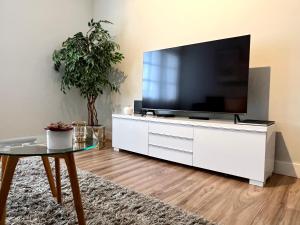 uma sala de estar com uma televisão grande numa cómoda branca em Flores & Campos Guest House em Santa Cruz de Tenerife