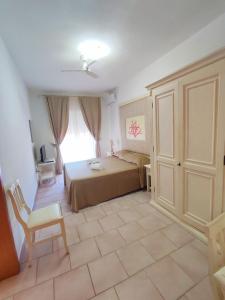1 dormitorio con 1 cama, 1 silla y 1 ventana en A.I.R. Hotel Gabbiano, en Isola Rossa