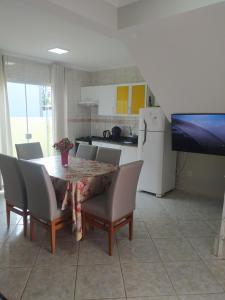 a dining room with a table and chairs and a kitchen at imóvel ideal para suas férias em Canto Grande in Bombinhas