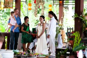 eine Braut und ein Bräutigam stehen neben einer Gruppe von Menschen in der Unterkunft The Emerald Krabi Beach Resort in Klong Muang Beach