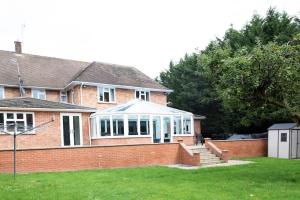 a brick house with a conservatory in a yard at Luxury 6 bedroom house with parking - Northwood in Northwood