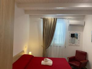 una camera con letto rosso, sedia e finestra di Villa Milisa a Terrasini