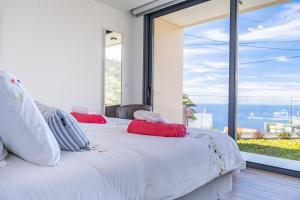 a bedroom with two beds and a large window at Villa Plumeria in Arco da Calheta