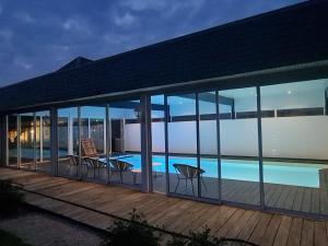 a house with glass walls and a swimming pool at Le Manoir des Marronniers in Sully