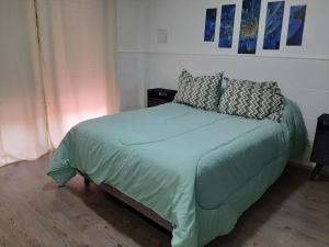 a bedroom with a bed with green sheets and pillows at DEPARTAMENTO CÉNTRICo LUJÀN 2 in Luján