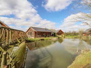 a building next to a river with a bridge at Lily-pad Lodge in Thorpe on the Hill