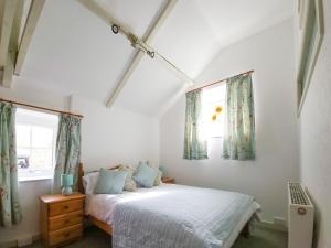 a bedroom with a bed and two windows at Y Beudy in Llannon