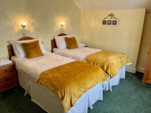 two beds in a hotel room with gold sheets at The Lookout in Ilfracombe