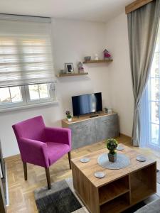 uma sala de estar com uma cadeira roxa e uma televisão em APARTMAN TAMARA LUX em Vrnjačka Banja