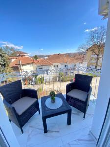 Duas cadeiras e uma mesa numa varanda com vista em APARTMAN TAMARA LUX em Vrnjačka Banja