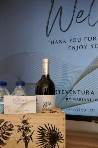 Fuerteventura Beach Vacations في بويرتو ديل روزاريو: زجاجة من النبيذ موضوعة على رأس صندوق خشبي