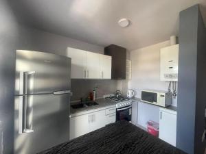 una cucina con armadi bianchi e frigorifero in acciaio inossidabile di Departamento por día para 4 personas con cochera cubierta en Bahía Blanca a Bahía Blanca