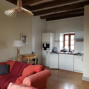 uma sala de estar com um sofá vermelho e uma cozinha em Gites Aubelle - La Maison Aubelle em Montreuil-Bellay