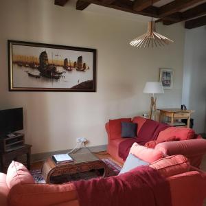 a living room with a red couch and a table at Gites Aubelle - La Maison Aubelle in Montreuil-Bellay