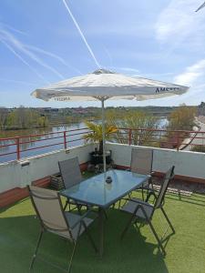 una mesa y sillas con una sombrilla en el balcón en A los Ojos del Río Duero en Zamora