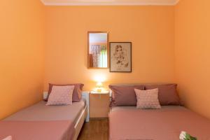 two beds in a room with orange walls at Michael's House in Vela Luka