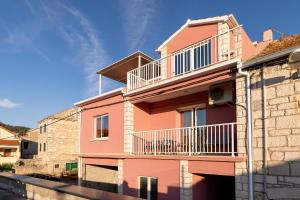 um edifício cor-de-rosa com uma varanda ao lado em Michael's House em Vela Luka