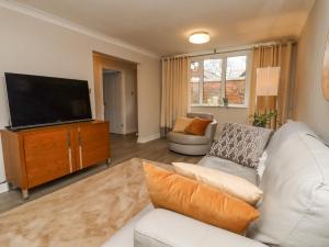 a living room with a white couch and a flat screen tv at Jasmine Cottage in Lytham St Annes