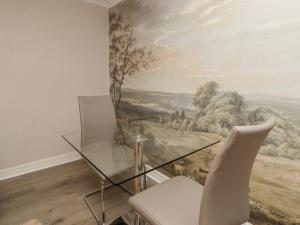 a dining room with a glass table and a painting at Jasmine Cottage in Lytham St Annes