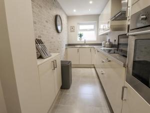 a kitchen with white cabinets and a brick wall at Jasmine Cottage in Lytham St Annes