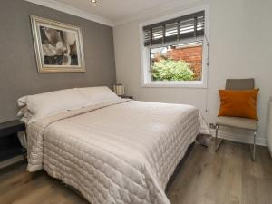 una camera da letto con un letto, una finestra e una sedia di Jasmine Cottage a Lytham St Annes