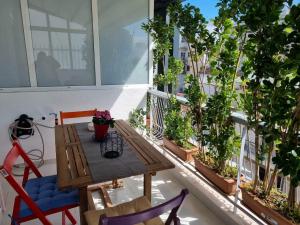 uma varanda com uma mesa de madeira, cadeiras e plantas em Modern studio apartment B em Atenas