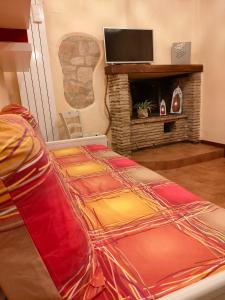 Cama en habitación con chimenea y TV en Nel vicolo dei Baci - Casa vacanze al Bacio, en Spello